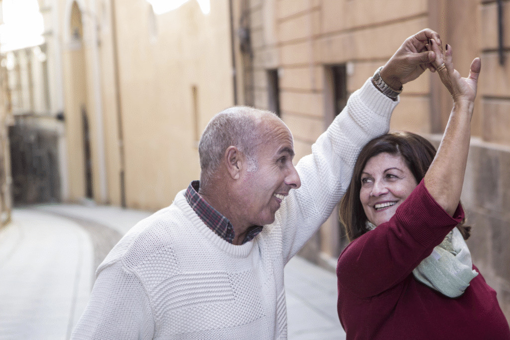 Smiling mature couple walking hand in hand on city street.