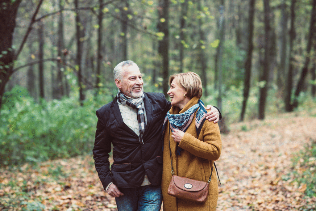 Happy mature couple walking in park holding hands.