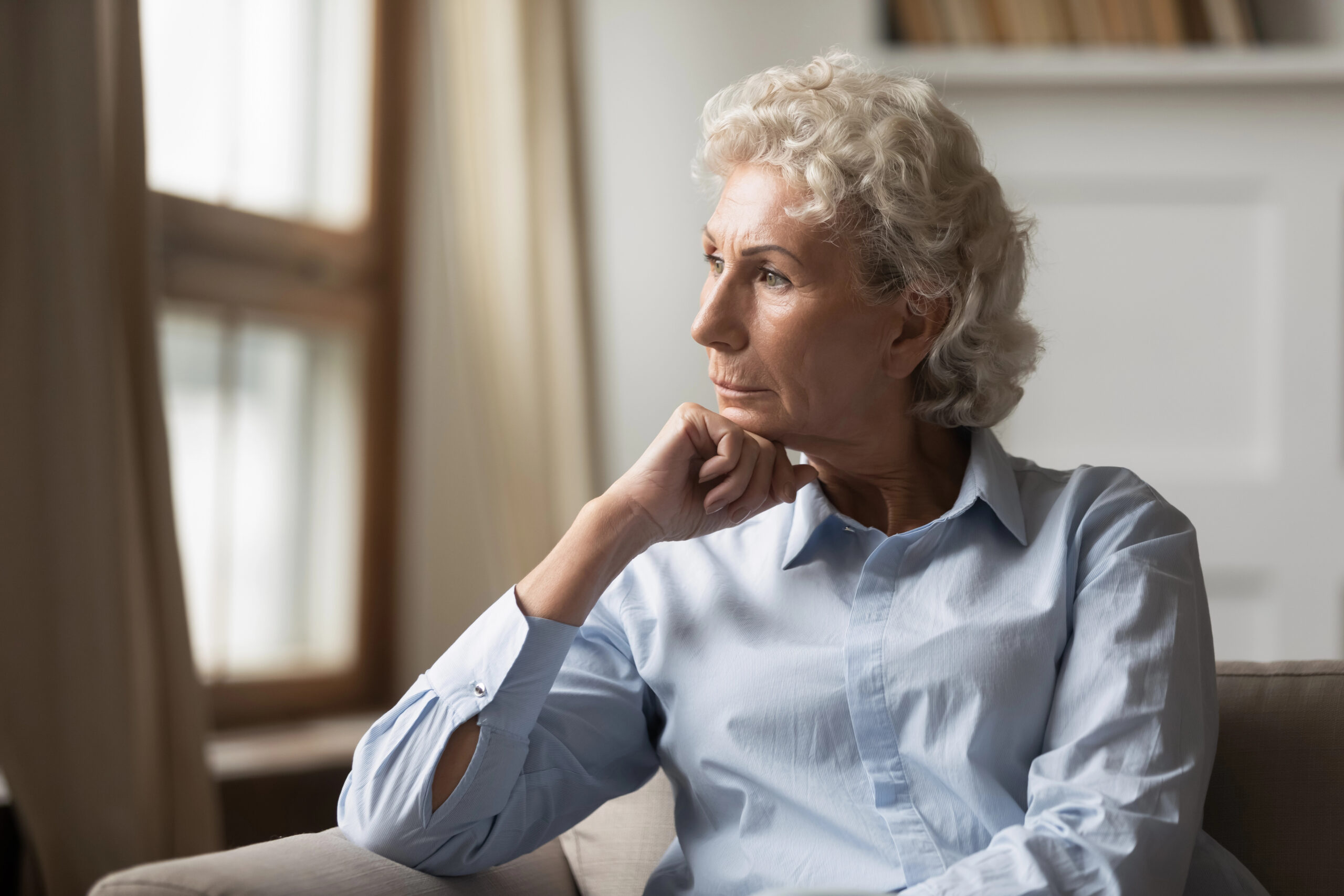 Senior woman looking out her window - looking depressed