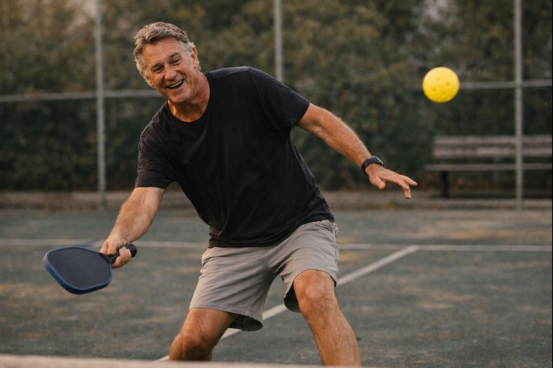 Man over 50 happily playing pickleball