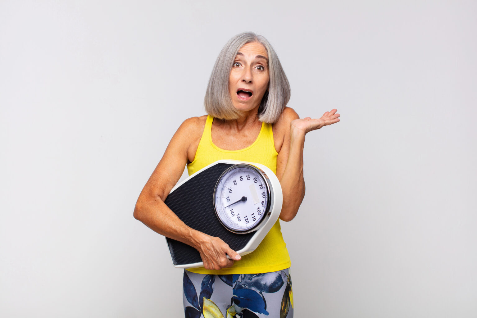 Why Weight Loss After 50 Can Be Hard (And Why You’re Not Doing Anything Wrong) woman over 50 with bathroom scale